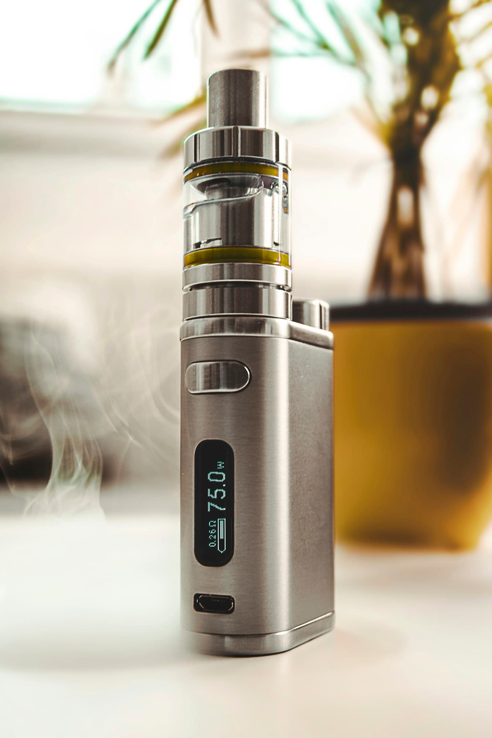 Red and black box-style vape mod with adjustable airflow resting on a rock outdoors